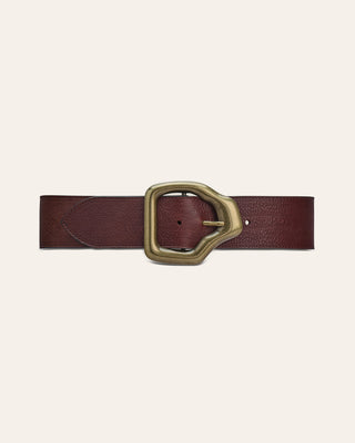 A dark reddish-brown leather belt with a textured finish and a large, antique brass buckle, displayed horizontally on a light cream background.