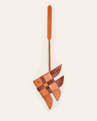 Cala Jade broen and orange leather bag charm shaped as a fish on a beige background