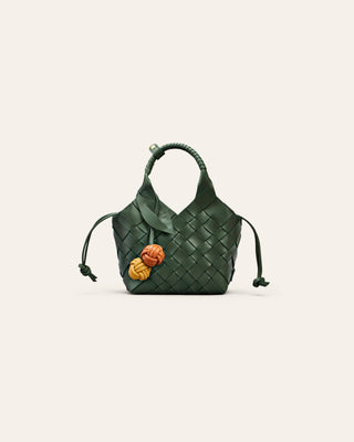 Cala Jade Misu Mini Green woven handbag with a leather bag charm on a light beige background