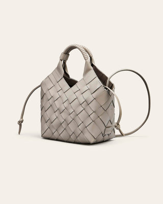 Cala Jade Grey woven leather handbag with a drawstring on a beige background
