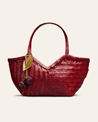 Cala Jade woven red handbag with decorative bag charm on a light beige background seen from the front