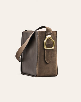 Brown leather handbag with a gold buckle on a light beige background
