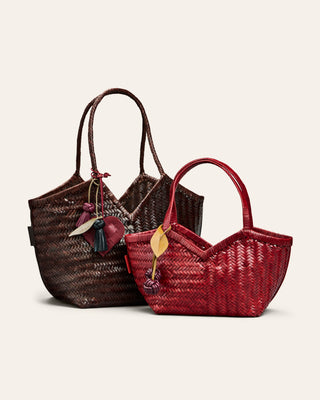 Two woven handbags, one brown and one red, on a light beige background with bag charms attached to the handles