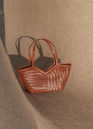 Brown woven handbag on a textured beige surface