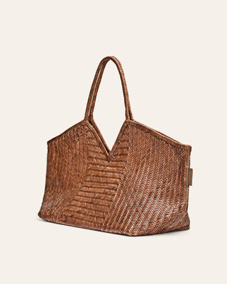 Large brown woven handbag on a beige background