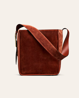 Rusty red leather crossbody bag on a beige background