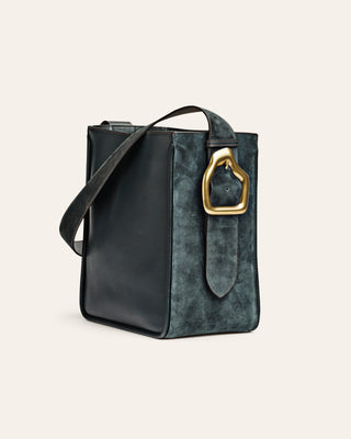 Green suede leather handbag with a gold buckle on a beige background