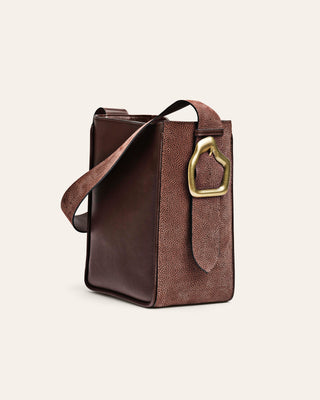Brown leather handbag with a gold clasp on a beige background