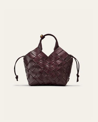 A burgundy woven leather bag on a beige background