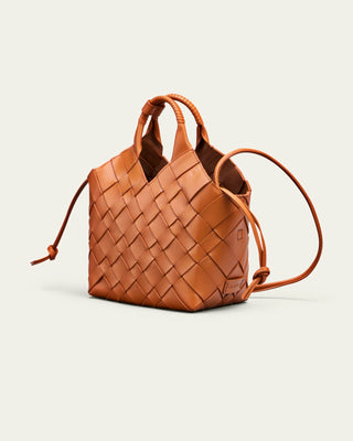 Cala Jade orange woven shoulder bag on a beige background seen from the side