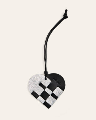 Cala Jade sparkling silver and black leather bag charm shaped as a heart on a beige background