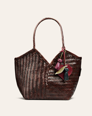 Woven handbag with decorative charm on a light beige background