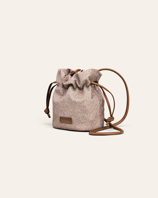 Cala Jade prutple sparkling drawstring bag with brown strap on a light beige background