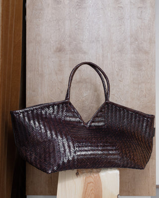 A brown leather bag on a wooden pidestal