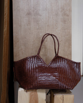 A brown leather bag on a wooden pidestal
