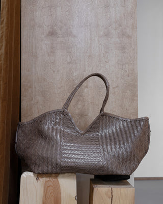 a beige leather bag on a wooden pidestal