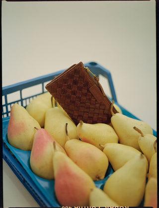 Brown woven basket on a blue tray with pears
